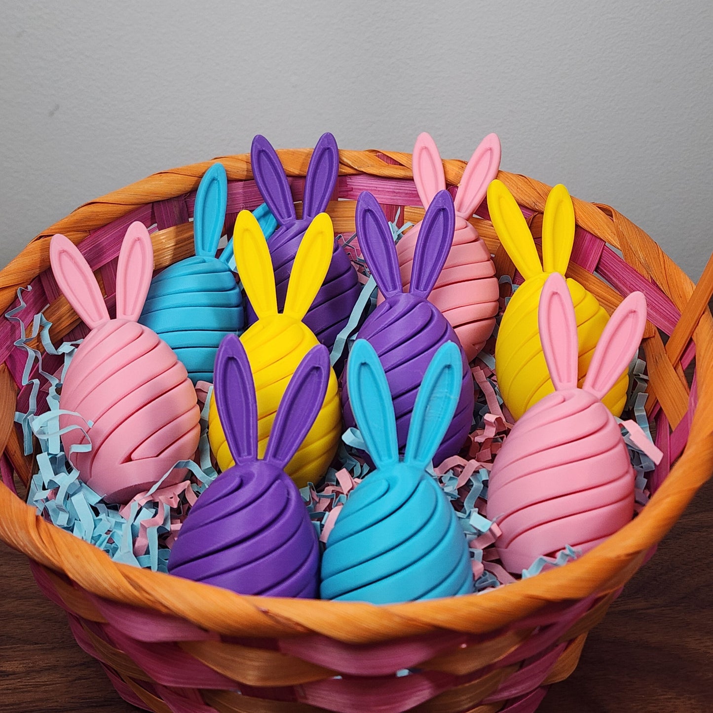 An easter basket of egg shaped spiral fidget toys with bunny ears in various pastel colours