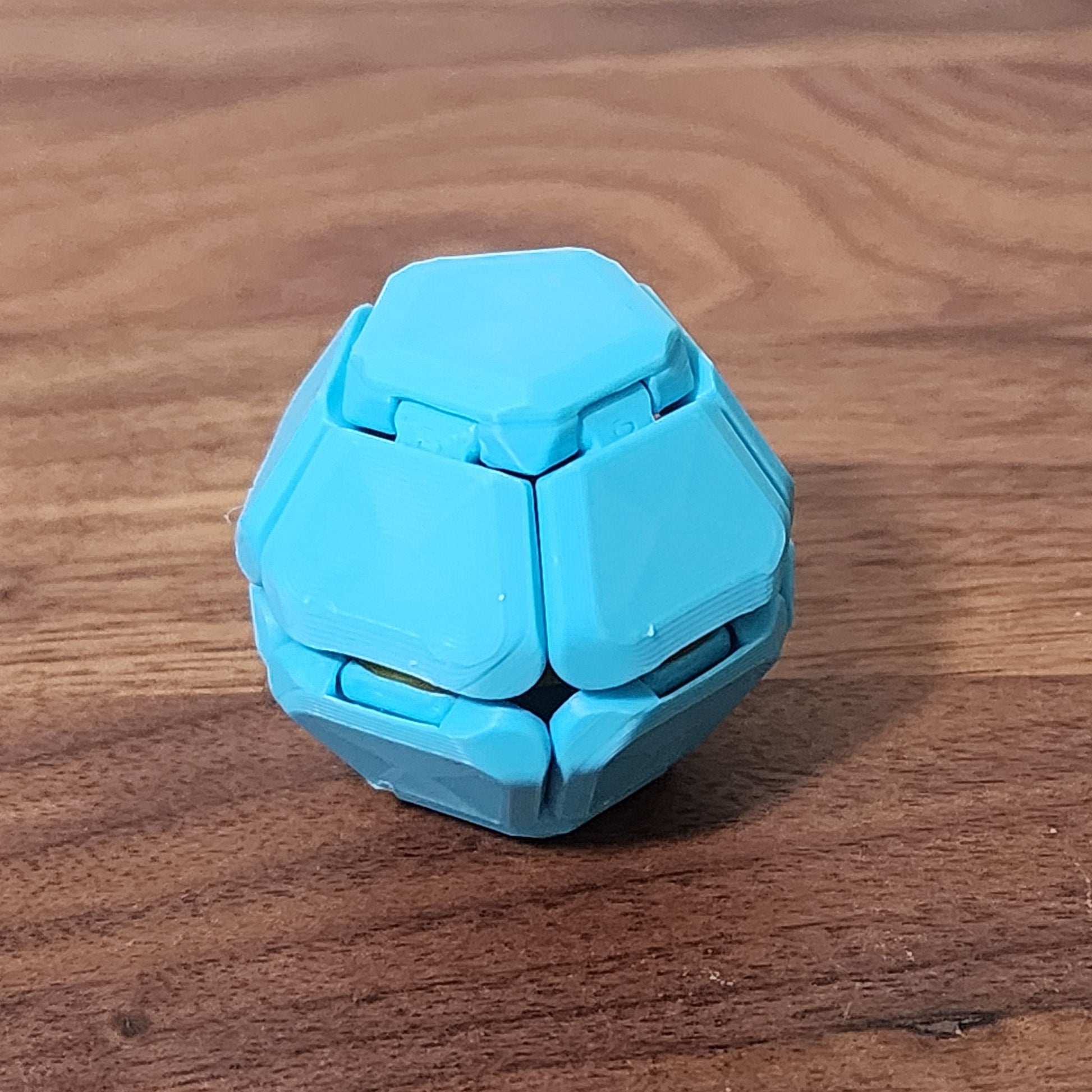 A single penta-click fidget sitting on a wooden desk